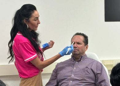 Person in pink shirt assisting another person with a procedure.